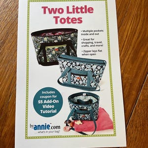 Può includere: Una pubblicità stampata per "Two Little Totes" con tre modelli di borse tote. Le borse hanno vari modelli e colori, con manici e cerniere. L'annuncio include testo sulle caratteristiche delle borse e un coupon.