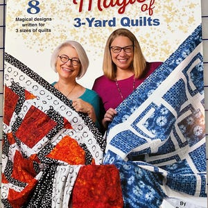 May include: A book cover titled "The Magic of 3-Yard Quilts" featuring two women holding colorful quilts. The cover includes text that reads "8 Magical designs written for 3 sizes of quilts" and the Fabric Cafe logo.