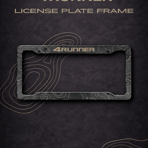 Puede incluir: Un marco de matrícula negro con un patrón topográfico y el texto "4RUNNER". El marco es rectangular con esquinas redondeadas y orificios de montaje. El fondo es oscuro con un diseño topográfico.
