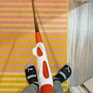 Pu&ograve; includere: Una mazza da golf con una testa argentata e un'asta marrone. L'impugnatura &egrave; arancione con un ausilio per l'allenamento bianco. L'immagine &egrave; ripresa in prima persona.