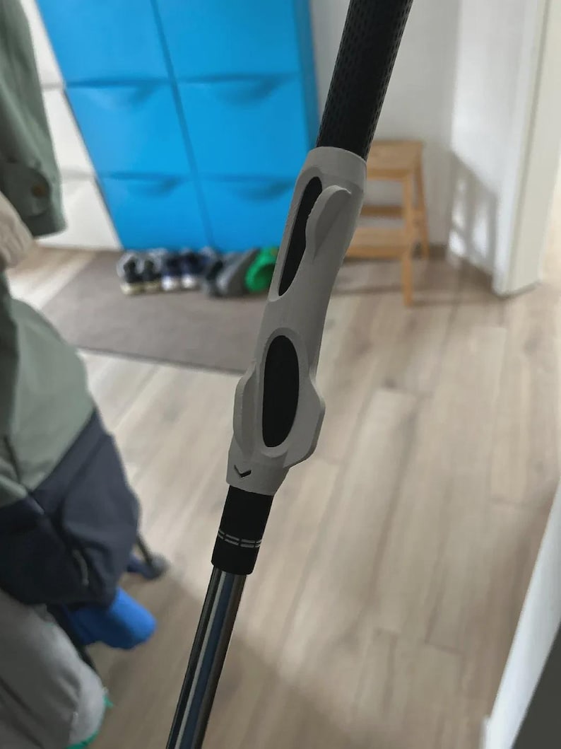 Pu&ograve; includere: Una mazza da golf con un'impugnatura nera e un'attrezzatura di allenamento grigia attaccata. L'attrezzatura di allenamento ha dettagli neri ed &egrave; progettata per aiutare con l'impugnatura e la meccanica dello swing. La mazza &egrave; argento e nera.