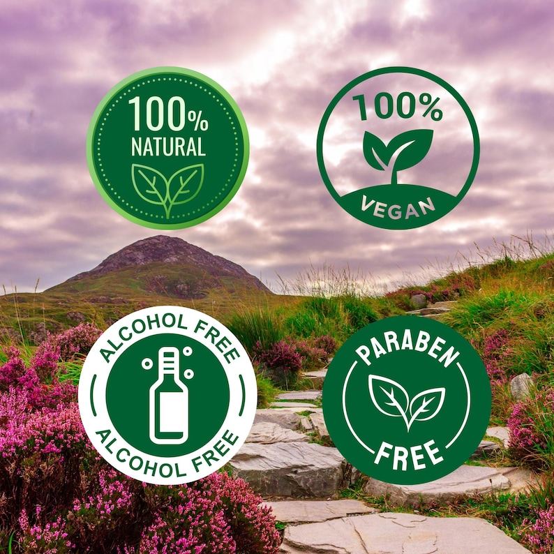 Puede incluir: Cuatro insignias circulares verdes con texto e iconos blancos. Las insignias dicen "100% NATURAL", "100% VEGANO", "SIN ALCOHOL" y "SIN PARABENOS". El fondo muestra una monta&ntilde;a, un camino de piedra y flores moradas.