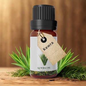 Puede incluir: Una botella de vidrio marrón de aceite de Kewra con tapa negra y etiqueta de papel. La etiqueta dice "Kewra" y presenta una ilustración de planta verde. La botella es de 10 ml. Hojas verdes rodean la botella.