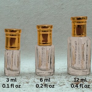 May include: Three clear glass perfume bottles with gold-colored caps. The bottles are labeled 3 ml (0.1 fl oz), 6 ml (0.2 fl oz), and 12 ml (0.4 fl oz). The bottles have text that reads "NORAH PERFUMES".