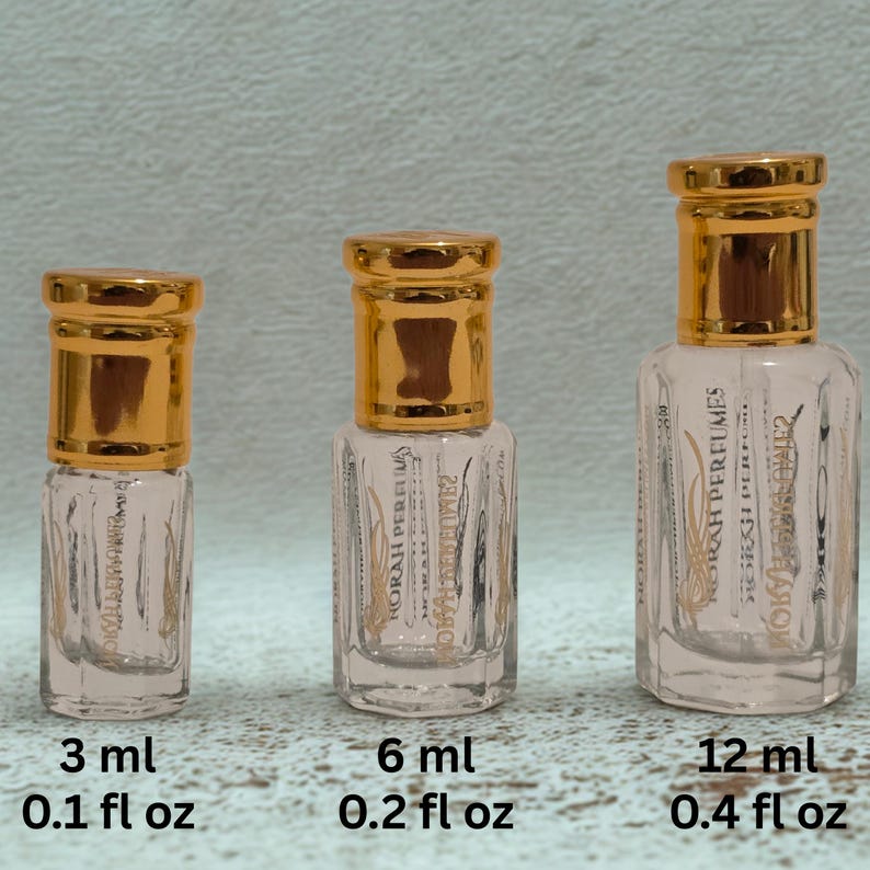 May include: Three clear glass perfume bottles with gold-colored caps. The bottles are labeled 3 ml (0.1 fl oz), 6 ml (0.2 fl oz), and 12 ml (0.4 fl oz). The bottles have text that reads "NORAH PERFUMES".