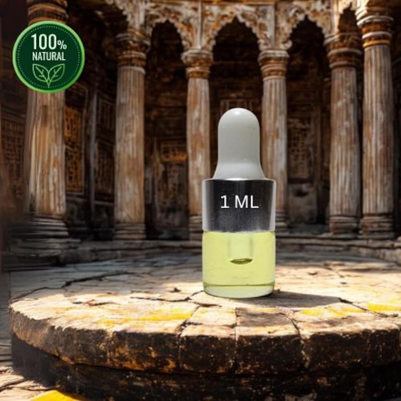 May include: A small glass bottle with a white dropper top, containing a yellow liquid. The bottle is labeled "1 ML". A green circular sticker with the words "100% NATURAL" is in the upper left corner. The background features an ancient architectural structure.