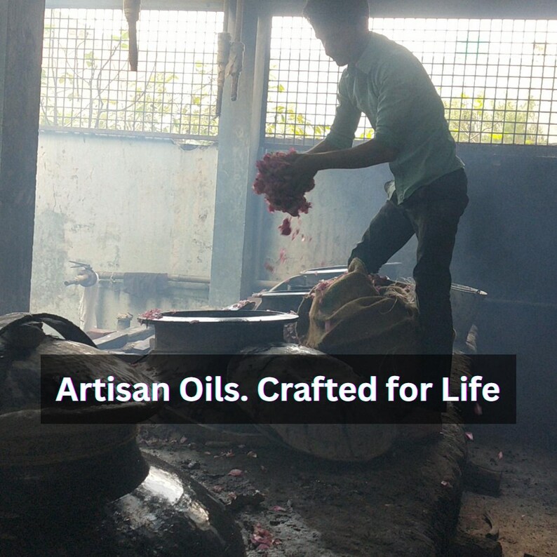May include: A person working with a large bundle of pink flowers, likely roses, in a workshop. The text "Artisan Oils. Crafted for Life" is displayed across the bottom of the image. The scene is dimly lit.