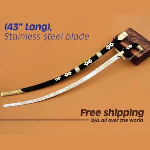 Puede incluir: Una espada decorativa con una hoja de acero inoxidable, de aproximadamente 109 cm de largo. La espada tiene una empuñadura negra con detalles dorados y una hoja blanca con diseños florales dorados. El texto "Stainless steel blade" está presente.