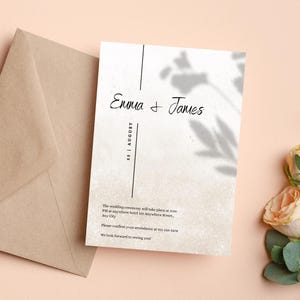 May include: A wedding invitation featuring the names "Emma & James" in elegant script. The date "22 | AUGUST" is vertically aligned. The invitation has a soft, textured background with a floral shadow design. A brown envelope is visible.