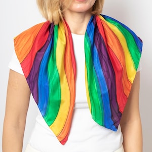 May include: A colorful rainbow-striped scarf with a wavy pattern. The scarf features a vibrant spectrum of colors, including red, orange, yellow, green, blue, and purple. The scarf is made of a silky material and is draped around the neck.