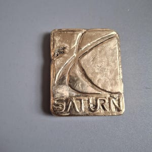 Saturn Corporation-logotyp i aluminiumbrons