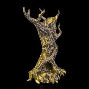 Puede incluir: Una detallada escultura de árbol dorada y gris con una calavera tallada en el tronco. El árbol tiene corteza texturizada y ramas intrincadas, sobre un fondo negro. La escultura es un objeto decorativo.