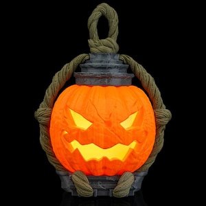 May include: A glowing orange pumpkin lantern with a carved face, set against a black backdrop. The lantern features a grey base and top, with a rope handle and accents. The carved face emits a warm yellow light, ideal for Halloween.