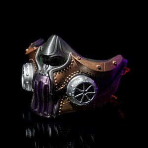 May include: A steampunk-style mask with a metallic finish. The mask features a combination of silver, bronze, and purple colors, with intricate details like rivets and circular accents. The design evokes a futuristic, industrial aesthetic.