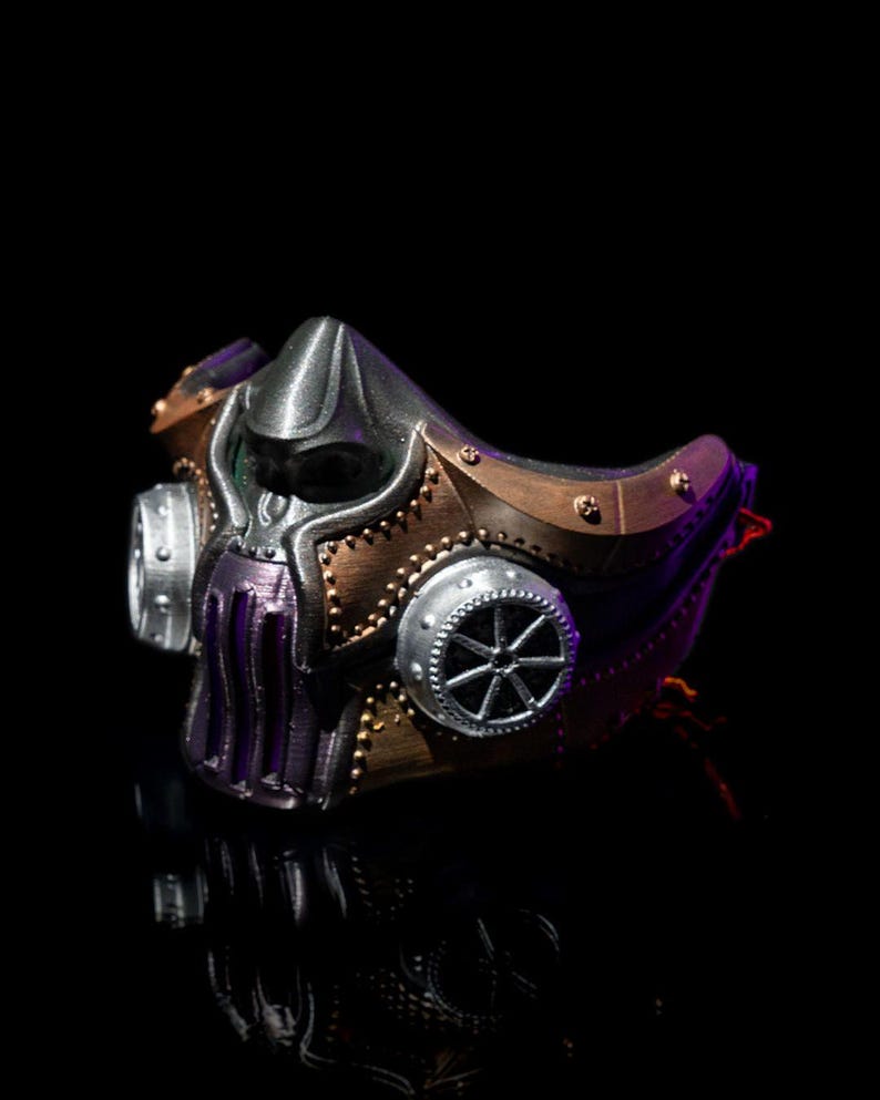 May include: A steampunk-style mask with a metallic finish. The mask features a combination of silver, bronze, and purple colors, with intricate details like rivets and circular accents. The design evokes a futuristic, industrial aesthetic.
