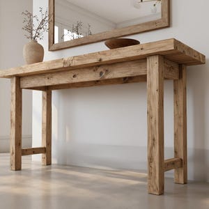 May include: A rustic wooden console table with a rectangular top and four sturdy legs. The table is made of light brown wood and has a natural, unfinished look. A vase with dried branches and a decorative bowl sit on top. The table is 60 inches long.