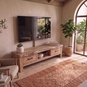 May include: A rectangular wooden media console featuring a natural live edge top, two drawers with black metal handles, and a central open storage shelf. The console is constructed from light-toned wood with visible grain patterns and sits on four sturdy legs.