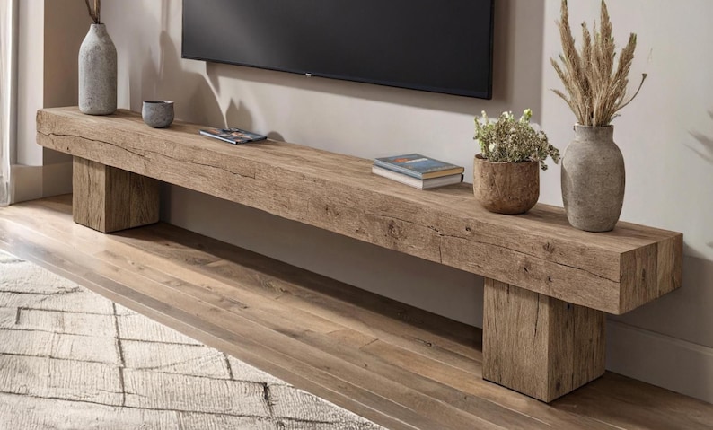 May include: A long, rectangular media console crafted from reclaimed light brown wood with a visible grain and natural cracks. The console is supported by two thick, block-style legs on either end, featuring a rough, textured surface finish.