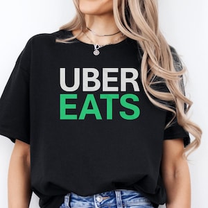May include: A black t-shirt with the words "Uber Eats" printed in white and green letters.