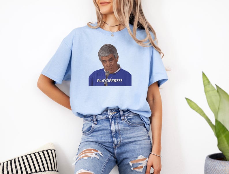 May include: A light blue t-shirt with a graphic of a man with a microphone saying "PLAYOFFS??" in white text.