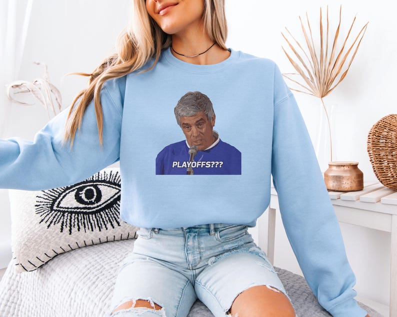 May include: A light blue sweatshirt with a graphic of a man with the text "PLAYOFFS??" printed on the front.