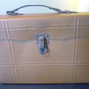 May include: A brown leather-like vintage carrying case with a metal latch and a label that reads "Fibra" in a diamond shape.