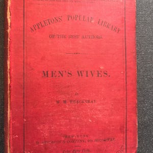 以下が含まれることがあります： W.M. Thackerayによる「Men's Wives」というタイトルのヴィンテージの赤い本。表紙には「Appleton's Popular Library of the Best Authors」という文字が白で表示されています。D. Appleton & Company, New Yorkから出版。