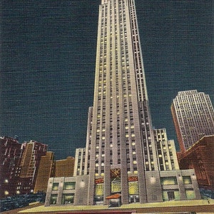 May include: A tall, white skyscraper with many windows illuminated at night. The building is surrounded by other buildings and a fountain with a statue in the foreground.