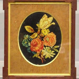 Pode incluir: Uma obra de arte emoldurada que apresenta um buquê de flores em tons de laranja, amarelo e verde. As flores são representadas em um estilo realista e são colocadas sobre um fundo preto. A moldura é feita de madeira e tem uma moldura dourada.