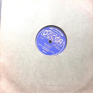 May include: A vintage vinyl record with a blue label featuring the text "THANKFUL" by Louis Armstrong and his Orchestra. The record is housed in a plain, light brown paper sleeve. The Decca label is visible.