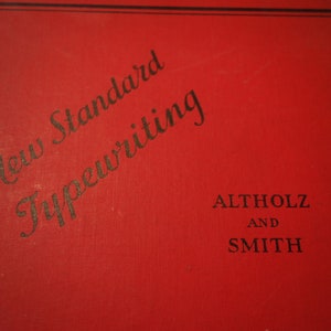 May include: A red book with the title "New Standard Typewriting" by Altholz and Smith.
