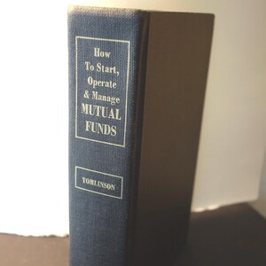 May include: A navy blue hardcover book titled "How To Start, Operate & Manage Mutual Funds" by Tomlinson.