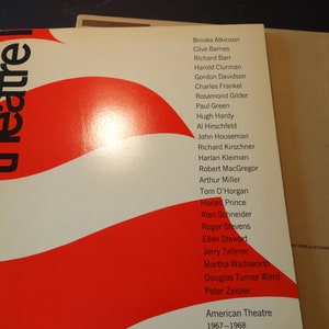 Op de afbeelding: Een boek getiteld "American Theatre 1967-1968" met een rood en wit omslagontwerp. Het woord "theatre" staat in grote, gestileerde letters. Een lijst met namen staat afgedrukt op de rechterkant van de omslag.