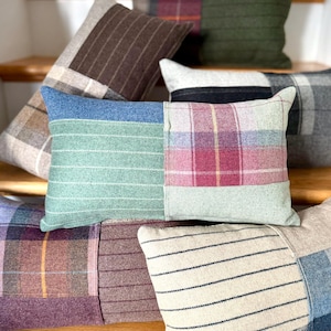 May include: A collection of decorative throw pillows in various colors and patterns. Pillows feature patchwork designs with plaid, striped, and solid fabric sections. Colors include red, green, blue, brown, and cream. The pillows are arranged on wooden stairs.