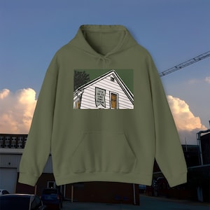 以下が含まれることがあります： 家のグラフィックと「It's ok to like emo again」というテキストが書かれたバナーが家の屋根からぶら下がっている、緑色のフード付きスウェットシャツです。