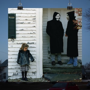 May include: An image of a young girl in a fur coat and plaid skirt standing near a white house. Two figures in black cloaks and skull masks stand on the porch. The scene is set against a blue sky.