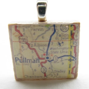May include: A square pendant featuring a vintage map of Pullman, Washington. The map is printed on a cream-colored background with red, blue, and yellow lines. The pendant is made of glass and has a silver bail.