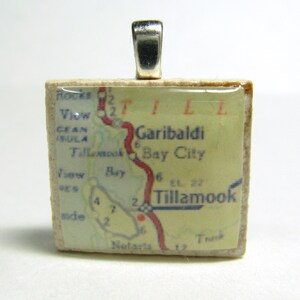May include: A square ceramic pendant with a vintage map of Tillamook, Oregon. The map features the town of Garibaldi, Bay City, and Tillamook Bay. The pendant has a silver bail.