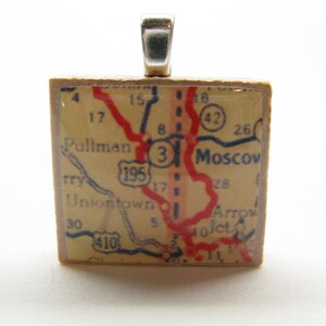 May include: A vintage map of Moscow, Idaho, with red roads and blue highways, is encased in a clear resin pendant. The pendant is attached to a silver bail.