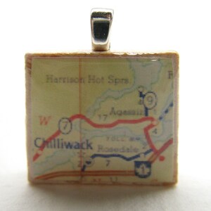 May include: A vintage map of Chilliwack, British Columbia, with a red and blue road map, is encased in a clear resin pendant. The pendant is attached to a silver bail.