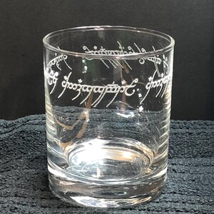 May include: A clear glass tumbler with the inscription "One Ring to rule them all, One Ring to find them, One Ring to bring them all and in the darkness bind them" etched around the top.