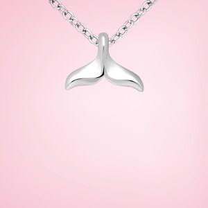 Pu&ograve; includere: Collana con pendente argentato a forma di coda di balena. Il pendente &egrave; liscio e lucido, con una forma curva. La catena &egrave; a maglie sottili. Lo sfondo &egrave; rosa tenue.