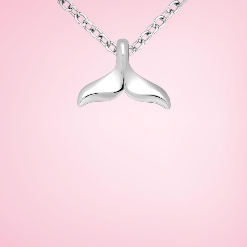 Pu&ograve; includere: Collana con pendente argentato a forma di coda di balena. Il pendente &egrave; liscio e lucido, con una forma curva. La catena &egrave; a maglie sottili. Lo sfondo &egrave; rosa tenue.