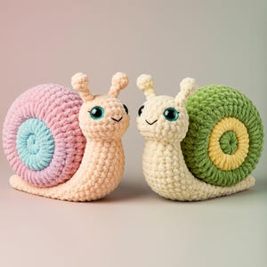 Può includere: Due chiocciole all'uncinetto fatte a mano. Una ha un guscio rosa e blu, l'altra un guscio verde e giallo. Entrambe hanno corpi color crema, grandi occhi blu e facce sorridenti. Le chiocciole sono di peluche e morbide.