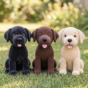 Puede incluir: Tres peluches de perro tejidos a ganchillo sentados en fila. El perro de la izquierda es negro, el del medio es marrón y el de la derecha es de color crema. Cada peluche tiene orejas caídas, ojos oscuros, nariz negra y una pequeña lengua rosa.