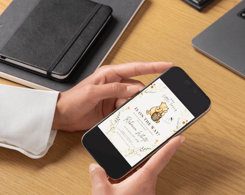 May include: A smartphone screen shows a baby shower invitation with a Winnie the Pooh theme. The invitation reads "Is on the Way!" and includes the name "Rebecca White". The design incorporates floral elements and a honey pot.