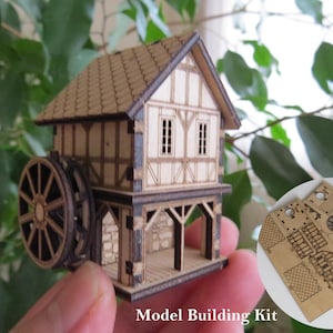 May include: A wooden model building kit of a small house with a water wheel. The kit includes laser-cut pieces and instructions for assembly. The model is shown partially assembled, with the water wheel and roof in place. The kit is labeled "Model Building Kit".