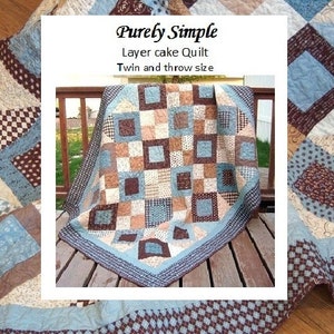 May include: A blue, brown, and cream quilt with a layer cake design. The quilt is labeled "Purely Simple Layer Cake Quilt Twin and Throw Size".