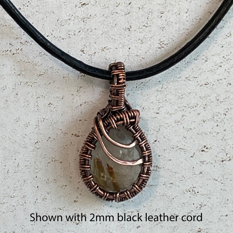 Small rutilated quartz pendant with woven wire setting shown with leather cord