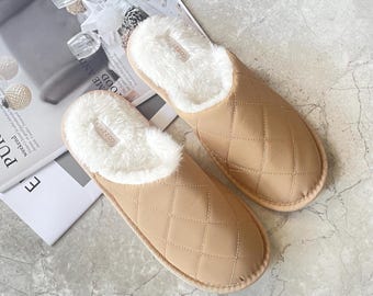 May include: A pair of tan quilted slippers with a white faux fur lining. The slippers have a closed toe and a slip-on design.